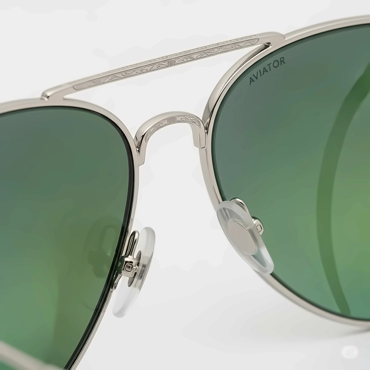 A close-up shot of the frame and lenses of a pair of high-quality green aviator sunglasses, showcasing the detailed metalwork and the vibrant color of the lenses.