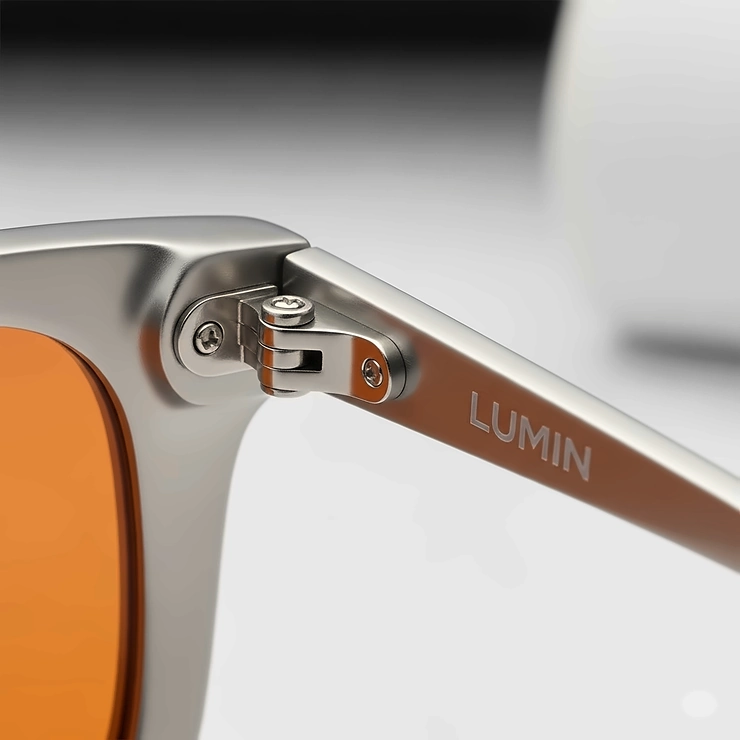 Close-up of the metal hinge and temple arm of orange lens sunglasses, showcasing the high-quality craftsmanship.