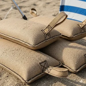 A close-up view of filled sand bags, showing the durable fabric and strong stitching, ready to anchor a beach tent.