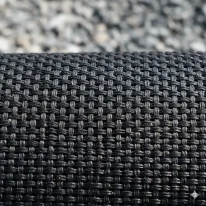 Close-up view of heavy-duty black mesh material, the ideal breathable tarp for hauling gravel, sand, and construction debris in a dump trailer.