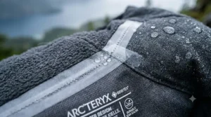 Close-up of the reinforced, taped seams on a rugged men's insulated rain jacket.