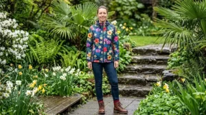 Woman styling a floral rain jacket with jeans and boots for a spring outfit.
