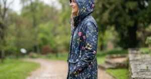 Side profile view of a waterproof floral rain jacket for women showing the adjustable hood.