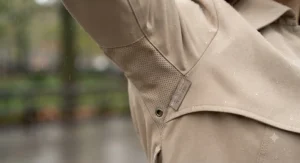 Close-up detail of the breathable fabric on a woman's waterproof trench coat.