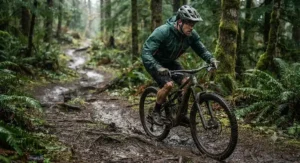 Mountain biker wearing a breathable windproof rain jacket for cycling on a muddy trail