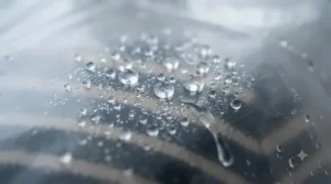 Rain droplets beading off the surface of a high-quality, waterproof clear plastic rain jacket.