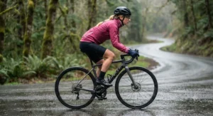 Side view of a woman wearing a pink rain jacket for cycling while riding her bicycle