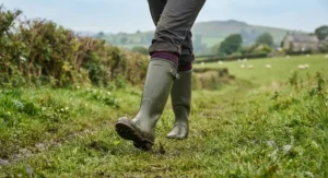 Classic green wellington boots women stepping through the countryside grass