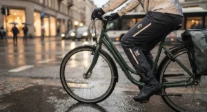 Close-up of a cyclist wearing breathable, reflective women's rain pants on a rainy city street