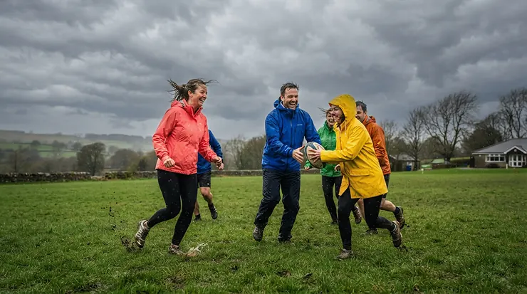 A family enjoying a backyard activity outfitted in a waterproof family rain gear set on a wet afternoon.