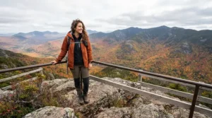 A hiker layering a lightweight down jacket for travel over a fleece during a mountain trail hike.
