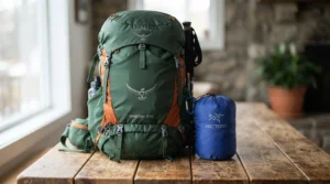 An 800 fill down jacket for backpacking compressed down to a tiny size next to a fully loaded trail pack.
