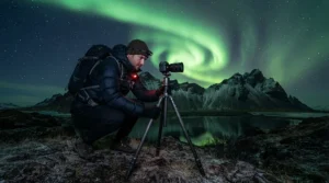 Photographer in an 800 fill down jacket for subzero temperatures operating a tripod under the aurora borealis